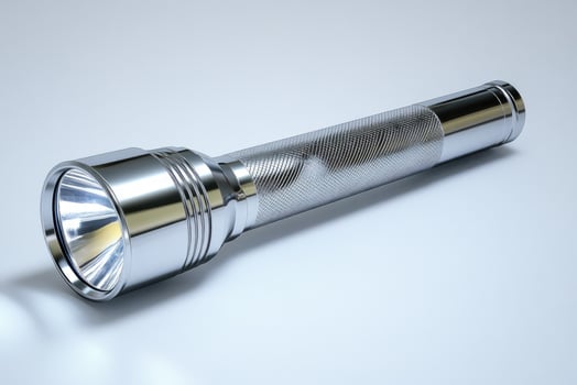 Chrome metal flashlight resting on white background photo
