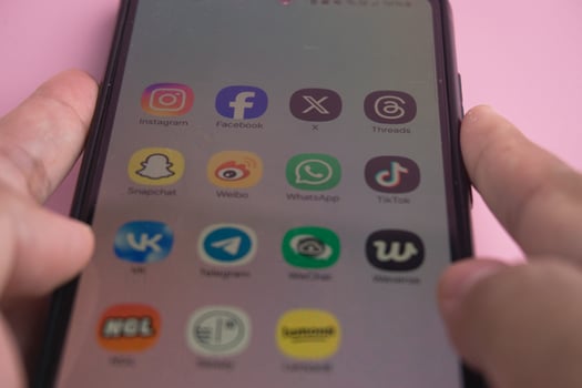 Close-Up of Smartphone Displaying Popular Social Media Applications on Pink Background photo