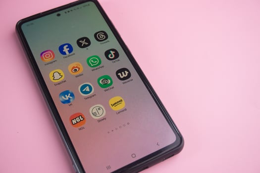 Close-Up of Smartphone Displaying Popular Social Media Applications on Pink Background photo