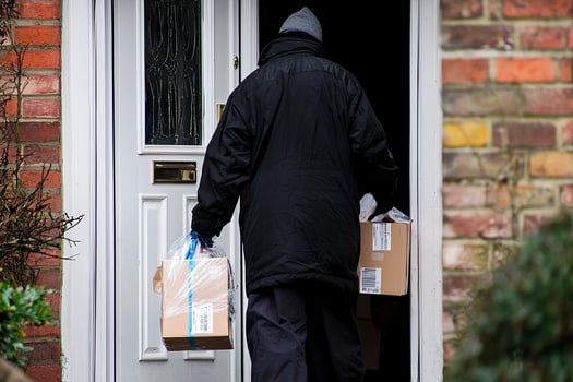 A man in a black coat and gloves is carrying two packages photo