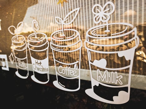 Creative Coffee Shop Window Art Featuring Various Hot Beverage Illustrations in a Cozy Urban Setting photo