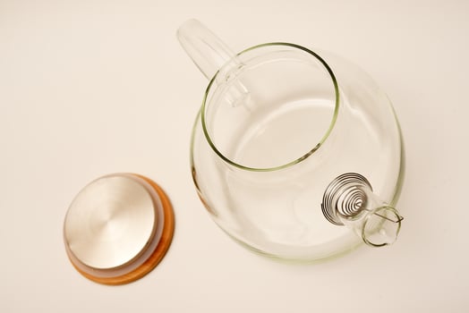 Glass teapot with wooden lid on a white background. photo