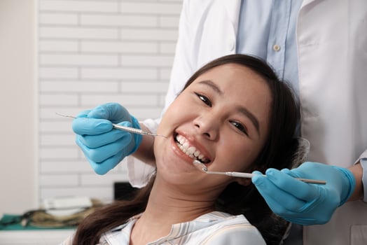 Close-up shot of beautiful Asian female face, white teeth, and cheerful face in dentist's hand, dental treatment with tooth whitening and cleaning in doctor hospital clinic, oral hygiene healthcare. photo
