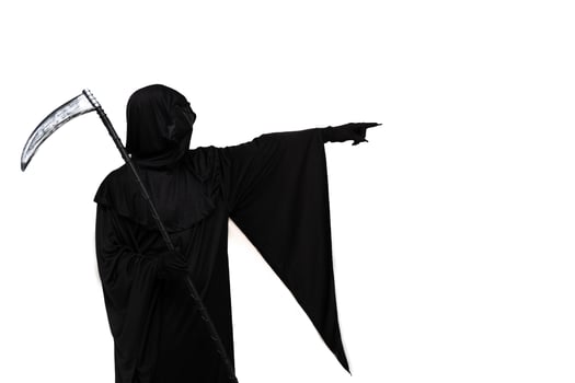 Grim reaper in Halloween costume holding scythe and pointing towards copyspace white background photo
