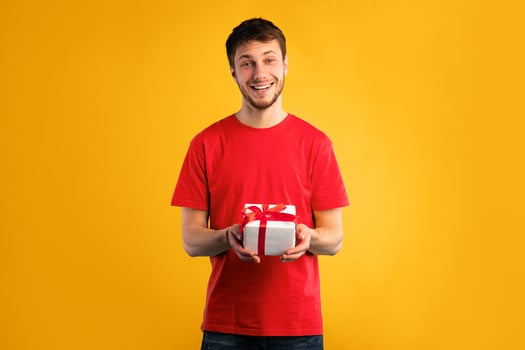 This Present Is For You. Young bearded man holding gift box isolated over turquoise studio wall photo