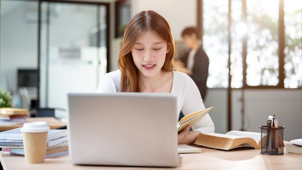 A beautiful Asian female college student working remotely from a cafe or studying in a library. photo