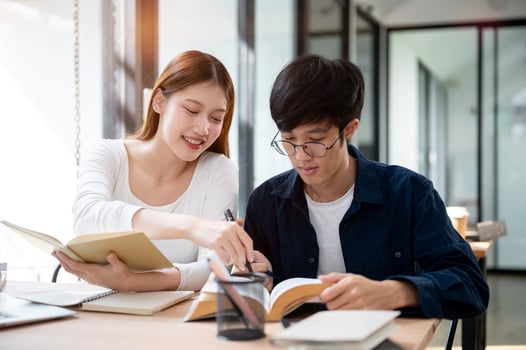 Two young Asian college students are studying and preparing for an exam together in a coffee shop. photo