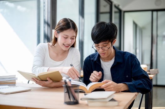 Two young Asian college students are studying and preparing for an exam together in a coffee shop. photo
