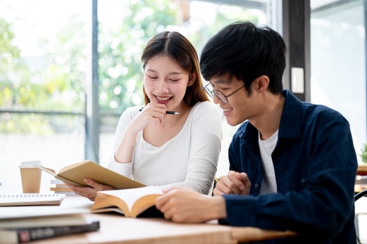 Two young Asian college students are studying and preparing for an exam together in a coffee shop. photo