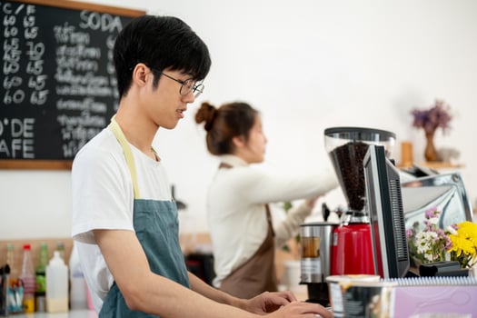 A friendly Asian male barista is working on a computer at the cashier checkpoint at the counter. photo