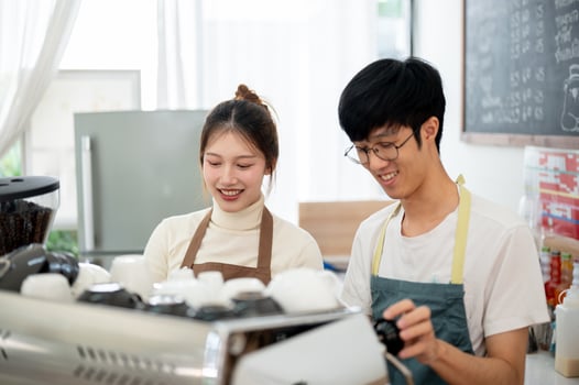Two friendly and happy Asian coffee shop staff members are preparing coffees to serve to customers. photo