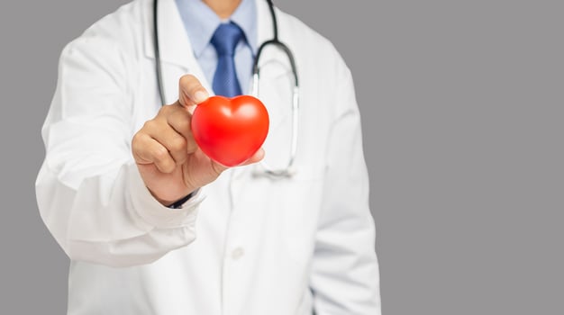 Cardiology concept. Close-up of hand doctor holding a red heart shape while standing in the hospital photo