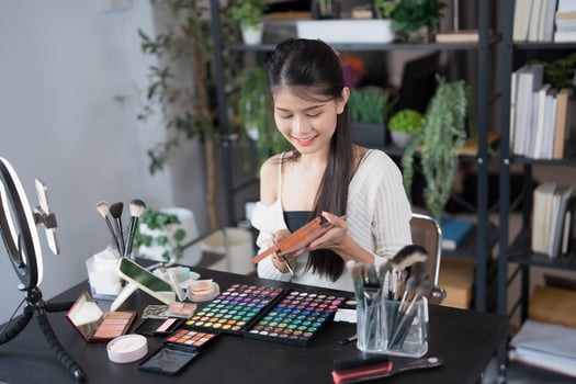 a beauty blogger woman is sitting at a desk with makeup products photo