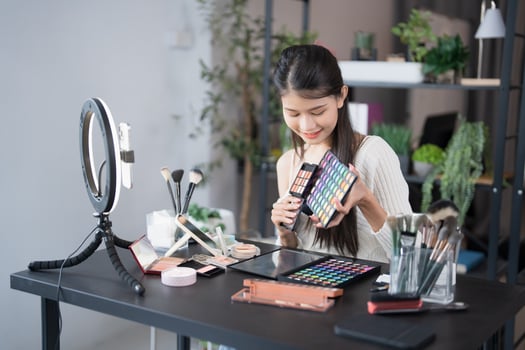 a beauty blogger woman is holding a makeup palette and looking at her phone photo