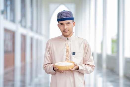 Muslim Hands are holding a wooden bowl of rice grains for zakat, an Islamic zakat concept. photo