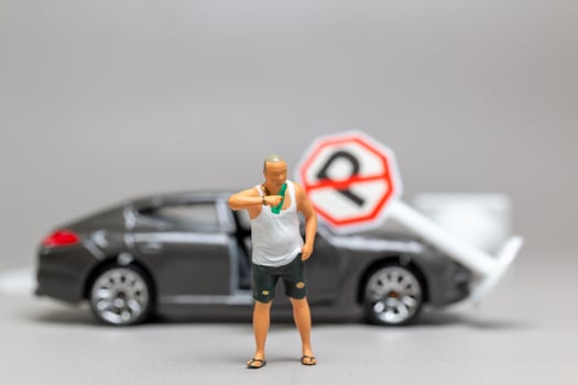 A Drunk driver holding a liquor bottle as he steps out of a car. concepts of reckless behavior, urban life photo