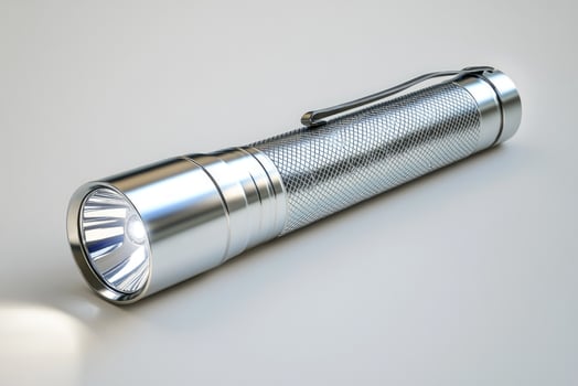 Chrome metal flashlight resting on white background photo