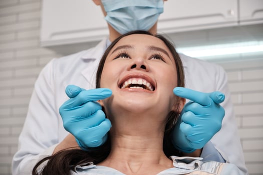 Close-up shot of beautiful Asian female face, white teeth, and cheerful face in dentist's hand, dental treatment with tooth whitening and cleaning in doctor hospital clinic, oral hygiene healthcare. photo