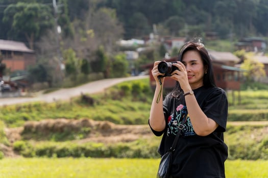 Woman photographer with big backpack taking photo of mountains and blue lake. Travel and hobby concept.