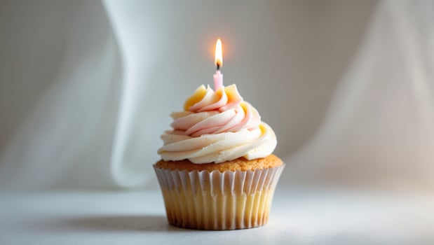 Celebrate with a bright cupcake topped with frosting and a candle for special occasionsCelebrate with a bright cupcake topped with frosting and a candle for special occasions. photo
