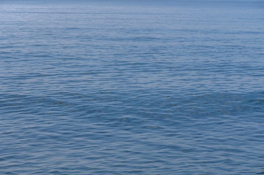 Calm waves gently lap against the shore at a tranquil seaside location in midday sunlight photo