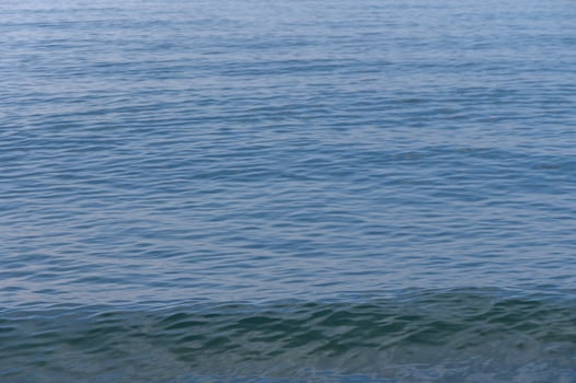 Gentle waves ripple across the tranquil surface of a serene blue ocean at midday photo
