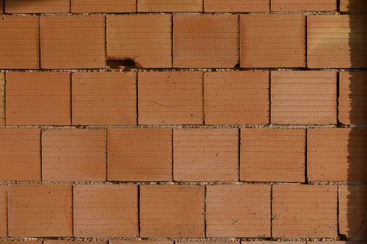 Textured wall showcasing warm tones and patterns in an urban setting with bright sunlight highlighting the bricks photo