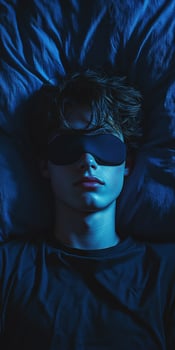 Young person resting in dark bedroom wearing sleep mask at night photo