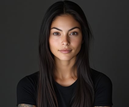 Portrait of a young woman with long hair and tattoos against a dark background photo