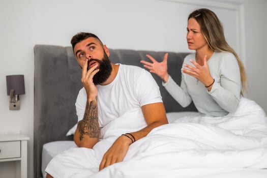 Couple is sitting in bed and arguing. The woman is angry with the man. photo