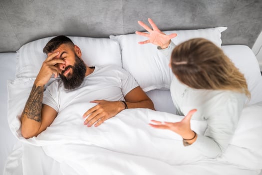 Couple is lying in bed and arguing. The woman is angry with the man. photo