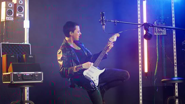 Female recording artist playing bass guitar in a nightclub concert, wearing a leather jacket and performing live with edgy bold attitude. Heavy metal musical talent in the studio. Camera A. photo
