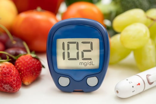 Asian hand holding digital glucose monitor measure with vegetable and fruit healthy food. photo