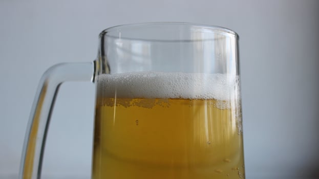 Top part of glass with handle filled of craft brown ale covered with foam closeup view photo