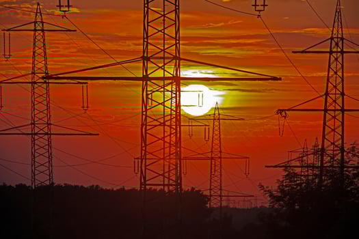 Power transmission towers silhouetted against a sunset sky photo