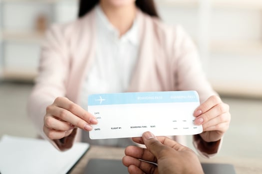 Female Travel Agent Giving Ticket To Unrecognizable Client Sitting In Tour Agency Office, Smiling To Camera. Tourism Management, Services For Travelers. Selective Focus On Boarding Pass photo