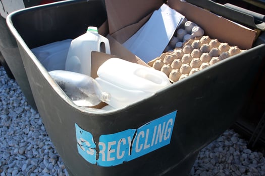 Recycling bin filled with cardboard and plastic waste outdoors. photo