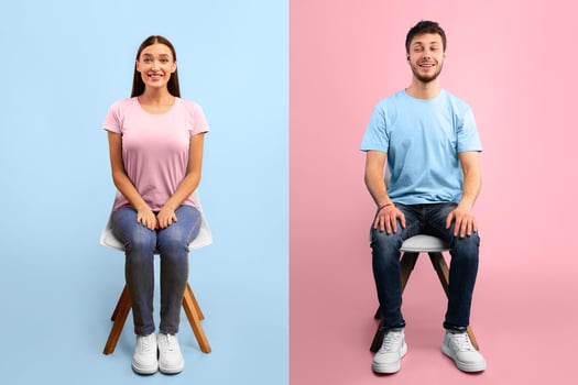 Studio portrait of young man and woman sitting on the chairs, copy space, orange and blue wall photo