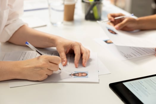 HR employee filling in application form after making sure candidate possesses skills needed to fulfil role. HR manager writing signature on documents after evaluating applicant photo