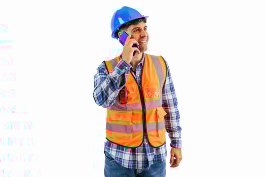 Engineer making a call with smartphone wearing orange vest and safety helmet white background photo