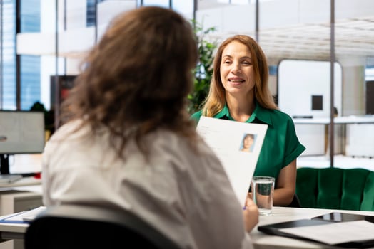 Human resources manager holding applicant CV, sitting at workplace desk during corporate office meeting. HR employer searching and selecting candidates to work for organization photo