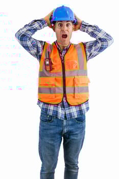 vertical Surprised construction worker holding his head with hands wearing orange vest and helmet photo