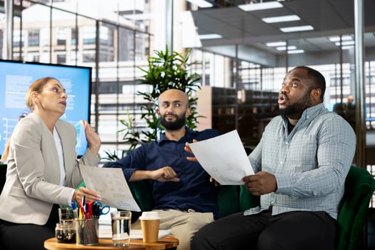 Upset diverse team of employees arguing after making mistake while writing revenue figures on documents in office. Mad staff members fighting during dispute over company statistical numbers photo