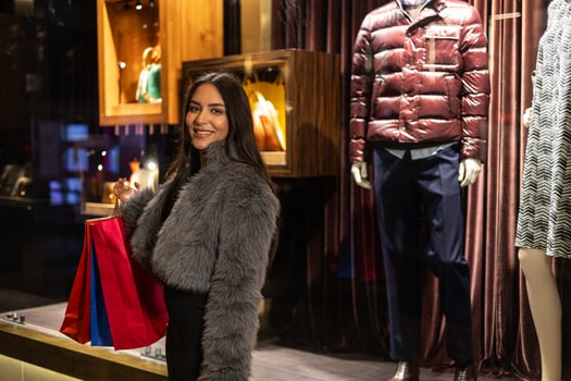 Young fashionable latina woman posing with paper shopping bags in front of clothing store photo