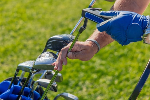 Close-up of senior golfer's hands carefully removing putter from golf bag photo