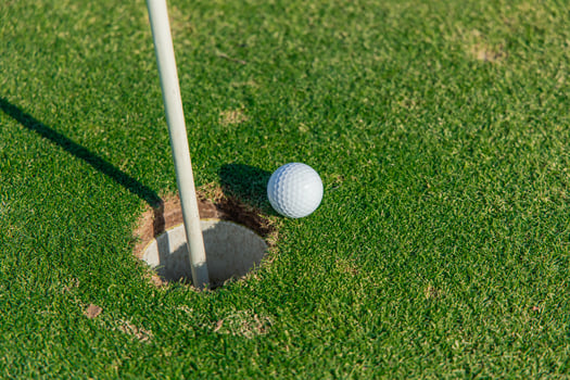 Close-up of a golf ball on the edge of the hole on the green photo