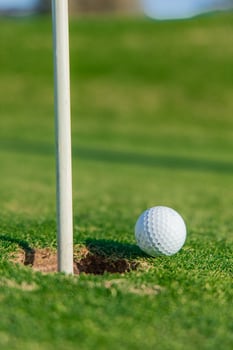 Golf ball balancing on the edge of the hole on the green photo