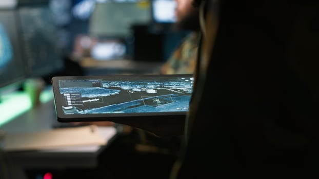 Army operative using tablet in command center housing operational missile defense system designed to intercept ballistic rockets. Close up of expert using tracking software on device, camera A photo