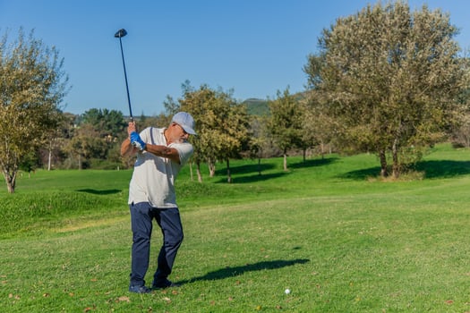 copyspace elderly golfer with cap and sunglasses hitting ball with driver during golf tournament photo