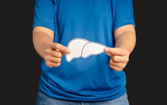 Hands holding a liver shape symbol made of paper while standing on a black background photo
